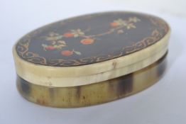 A 19th century horn box of oval form having gilded borders  with inset decorative foliate spray
