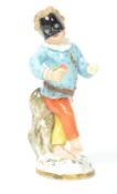 A 18th century Meissen ceramic Masquerade figurine of a boy with mask raised on a circular