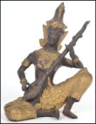 A 20th century Oriental figurine of a deity /  Buddha playing a lute having an ebonised body with