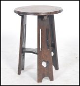 An Arts and Crafts oak tripod occasional table, the three splayed legs fret carved with teardrop