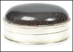 A sterling silver pill box of oval form having a hinged lid with large tigers eye stone to top.