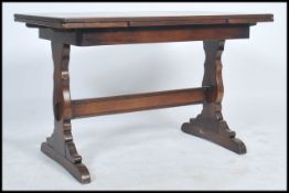 A mid 20th Century utility style furniture oak draw leaf dining table raised on standing on shaped