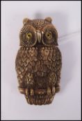 An unusual novelty brass vesta case in the form of an owl perching on a branch with yellow glass