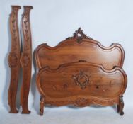 An antique style French Walnut double bed frame, the shaped headboard with foliate scroll carved