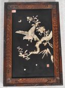 An Oriental shibayama panel on an ebonised back with carved scenes of birds and trees in an ornate
