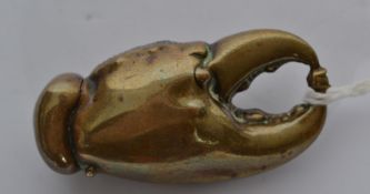 A late 19th century brass novelty vesta case in the form of a lobster claw clutching a pearl.