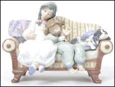A Lladro ceramic figurine group entitled ' Big Sister ' depicting two children on a sofa with dog,