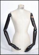 A retro vintage 20th century mannequin bust having articulated ebonised arms with notation to front.