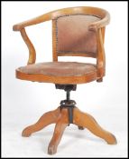 A vintage early 20th century Captains swivel armchair raised on a quadruped base with swivel