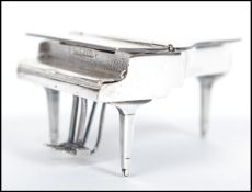 A sterling silver miniature grand piano raised on