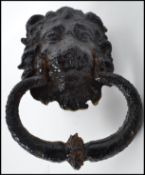 A 19th century cast iron door knocker in the form of a lion having an ebonised painted finish.
