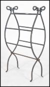 A decorative 20th century wrought iron metamorphic log basket, scroll work  design having a lever