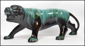 A large 20th century Blue Mountain pottery figure of a tiger in a deep black and blue drip glaze