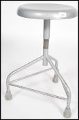 A vintage retro 20th century industrial medical stool raised on a tubular tripod base with revolving