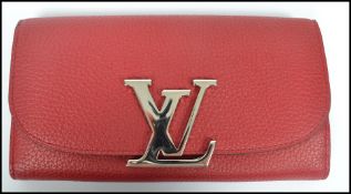An as new Louis Vuitton red grain leather ladies designer clutch bag with opening compartments.