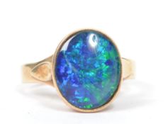A 9ct gold vintage opal - doublet ring having a large central opal mounted in a pierced and sloped