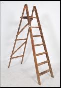 A vintage Industrial 20th century pine workmans ladders with a-frame supports and folding having