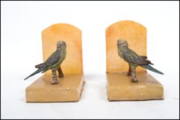 A pair of early 20th century cold painted bronze / spelter and alabaster parrot bookends. Each of