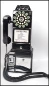 An American style contemporary coin operated wall telephone by Wild and Wolf having a ring dial