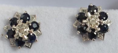 A pair of white gold and sapphire diamond cluster earrings in flower / star form complete in the