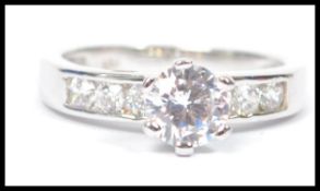 A silver solitaire engagement ring with prong set cz stone with further cz adorned shoulders to