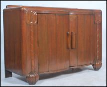 An early 20th century Art Deco oak serpentine fronted buffet with twin doors under drawers opening