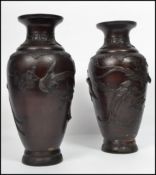 A pair of 19th century Oriental Bronze vases raised on a circular foot decorated in relief with
