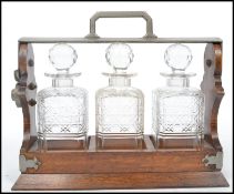A 19th century oak and white metal tantalus having 3 cut glass decanters. The shaped top with