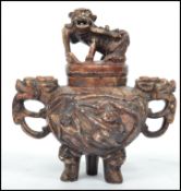 An unusual Oriental Chinese carved stone teapot raised on tripod base depicting lions, monkey and