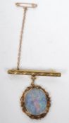 A 9ct gold and opal - doublet fob brooch having a chased decorated bar with an opal drop having a