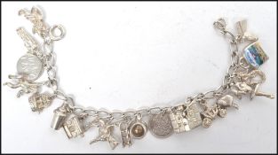 A vintage silver charm bracelet having various charms to include coin, pixie, typewriter, horse,