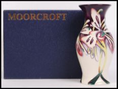 A Moorcroft ceramic tube lined vase decorated in the Joy pattern with impressed marks and painted
