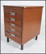 A retro 1970's teak wood filing chest of drawers having a bank of drawers raised on stub legs