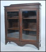 A 1930's oak bookcase display cabinet raised on bracket feet having twin doors with shelves inside