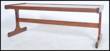 A retro 1970's G-Plan coffee table in teak and tiles with glass top being raised on shaped legs