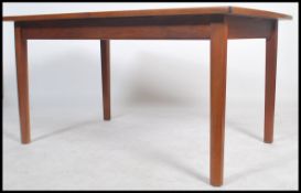 A large 1970's retro teak wood extending dining table of Danish influence being raised on turned