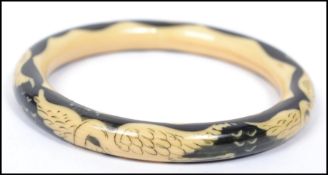 A vintage 20th century cream and black lucite bangle bracelet depicting storks in flight.