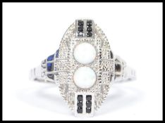 A ladies silver dress / cocktail ring inset with sapphires and opals to the centre. Of shield form