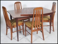 A Danish mid century teak extending dining table being raised on turned legs with fitted frieze