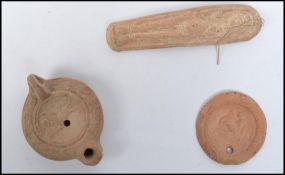 A group of three Roman stone items to include a devotional figurine, medallion coin and lamp base.