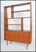 A 1970's Danish teak wood room divider bookcase being raised on tapered legs with cupboard base with