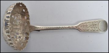 A silver hallmarked tea caddy strainer spoon having a pierced bowl and decorative handles.