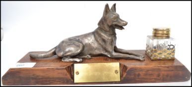 An early 20th century inkwell mounted on a wooden plinth with large cast figure of an Alsatian dog