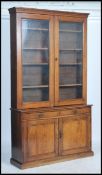 A late Victorian oak two section library bookcase cupboard having glazed doors to the upper