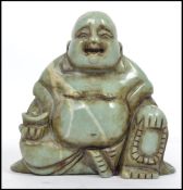 An Oriental Chinese carved soapstone seated laughing Buddha holding a prayer bead necklace in one