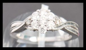 A hallmarked 9ct white gold and diamond ring. The ring having a  having 7 diamonds in a cluster