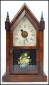 A 19th century American gingerbread mahogany cased mantle alarm clock by Waterbury having an