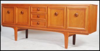 A 1970's teak sideboard unit having three drawers to centre flanked by twin door cupboards having