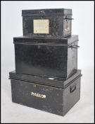 A group of three vintage 20th century graduating ebonised metal safe trunks, each with fitted