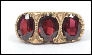 A hallmarked 9ct gold three stone ruby garnet ring having a pierced heart gallery mount with three